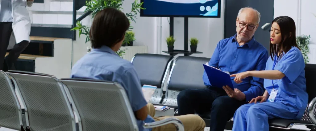 Healthcare claims processing support specialist assisting a patient with medical documentation in a healthcare facility waiting area