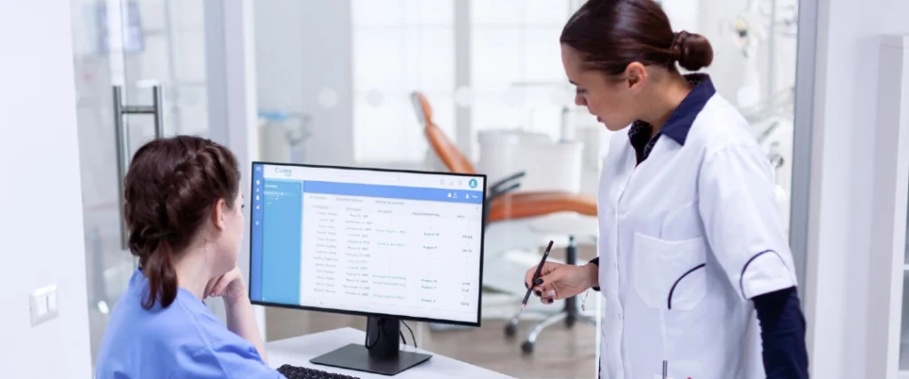 Healthcare professional assisting a patient scheduling specialist using an electronic appointment management system for patient scheduling outsourcing.