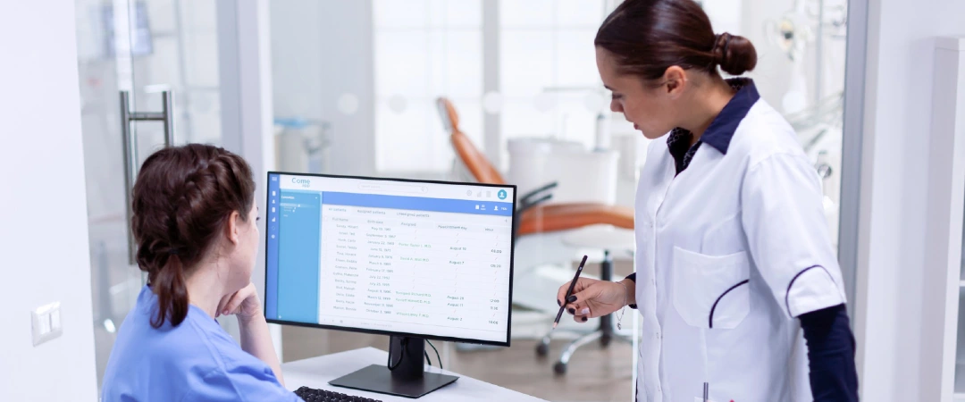 Healthcare professional assisting a patient scheduling specialist using an electronic appointment management system for patient scheduling outsourcing.