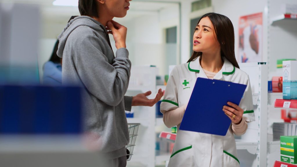 Pharmacist discussing medication concerns with a patient at a pharmacy counter.