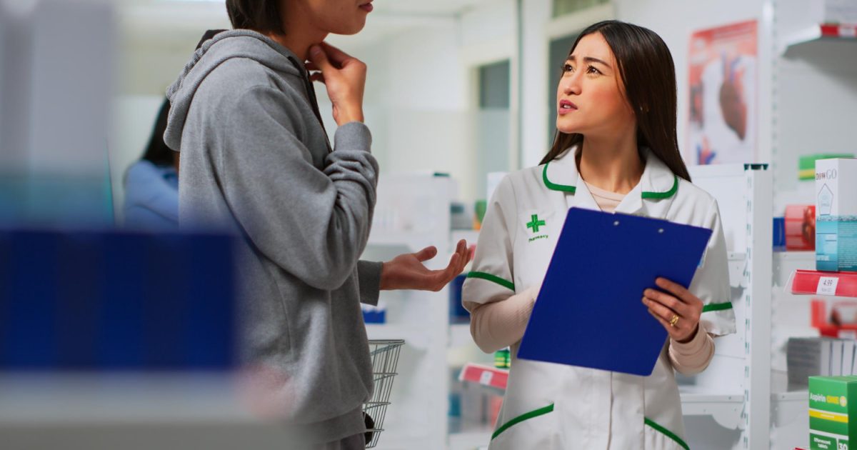 Pharmacist discussing medication concerns with a patient at a pharmacy counter.