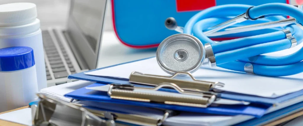 Durable medical equipment reimbursement documents with a stethoscope, clipboard, and medical supplies on a healthcare office desk.