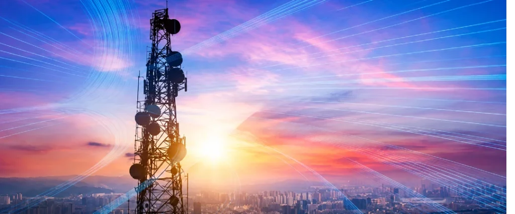 Telecommunications tower transmitting wireless signals over a US city at sunset