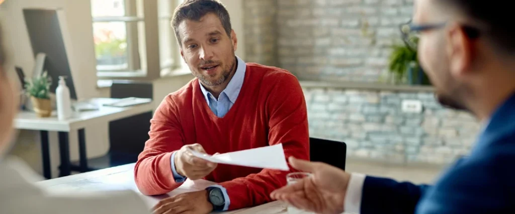 Commercial loan workout meeting with borrower and lending professionals reviewing documents