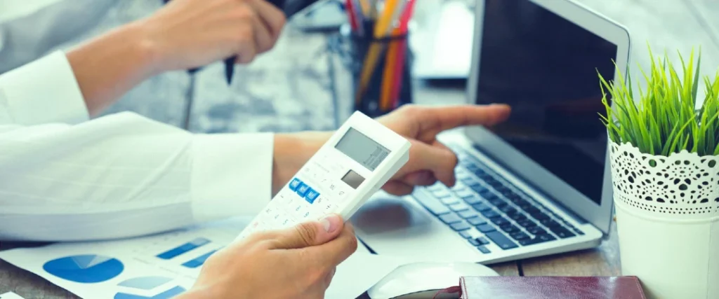 Loan processing professional reviewing financial documents and data on a laptop