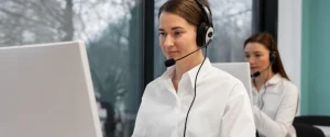 Healthcare customer service representatives wearing headsets and assisting members at computer workstations in a contact center.