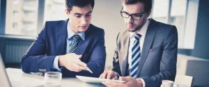 Finance professionals reviewing financial reports and analyzing business data during an office meeting.