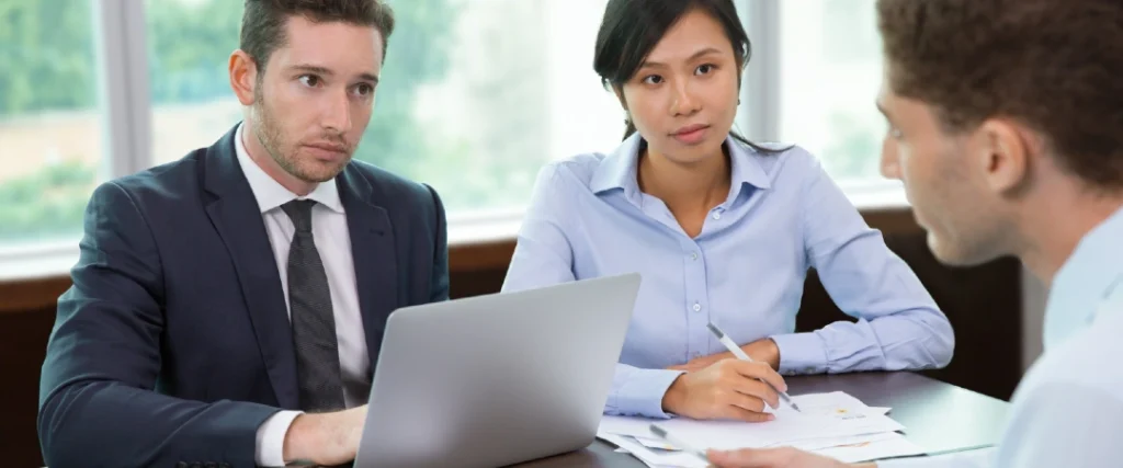 Business professionals reviewing documents and discussing financial information in an office meeting.