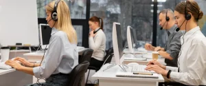 Call center agents wearing headsets and assisting customers at their computer workstations.