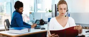 Insurance customer service agents handling calls in a professional office environment.